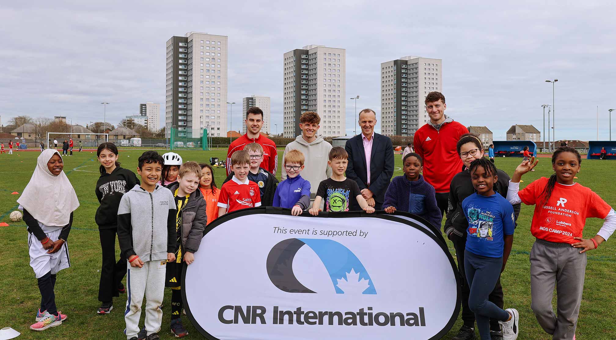 An image of CNR International Managing Director & VP Finance Barry Duncan with children, coaches and AFC Player Leighton Clarkson at Russell Anderson Foundation Easter Camp 2025